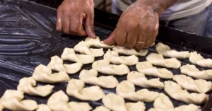 A tortellinatrice is a pasta-making machine specifically engineered to produce tortellini by automating the folding, filling, and shaping process.